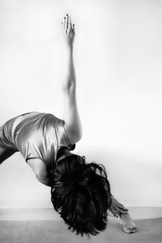 A woman gracefully practicing yoga in a black and white artistic setting, showcasing flexibility and balance.