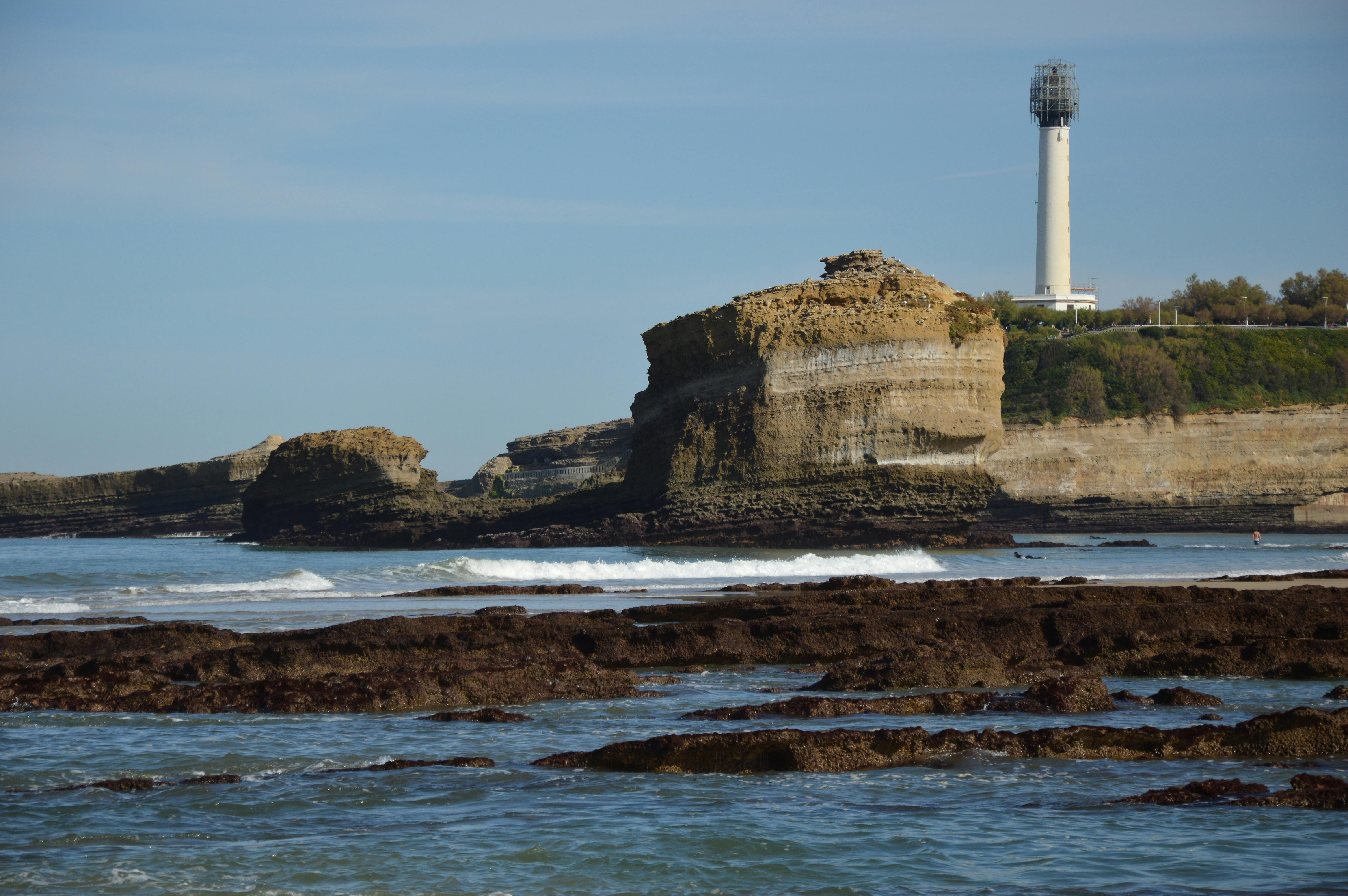 Biarritz lighthouse standing sentinel on coastal cliff with Atlantic waves crashing below at golden hour