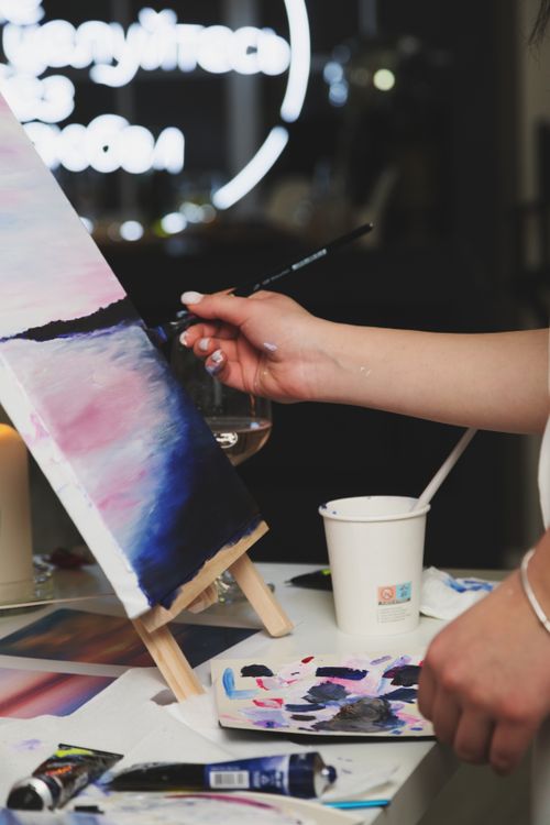 Free A woman painting a serene landscape on canvas, expressing creativity and art. Stock Photo
