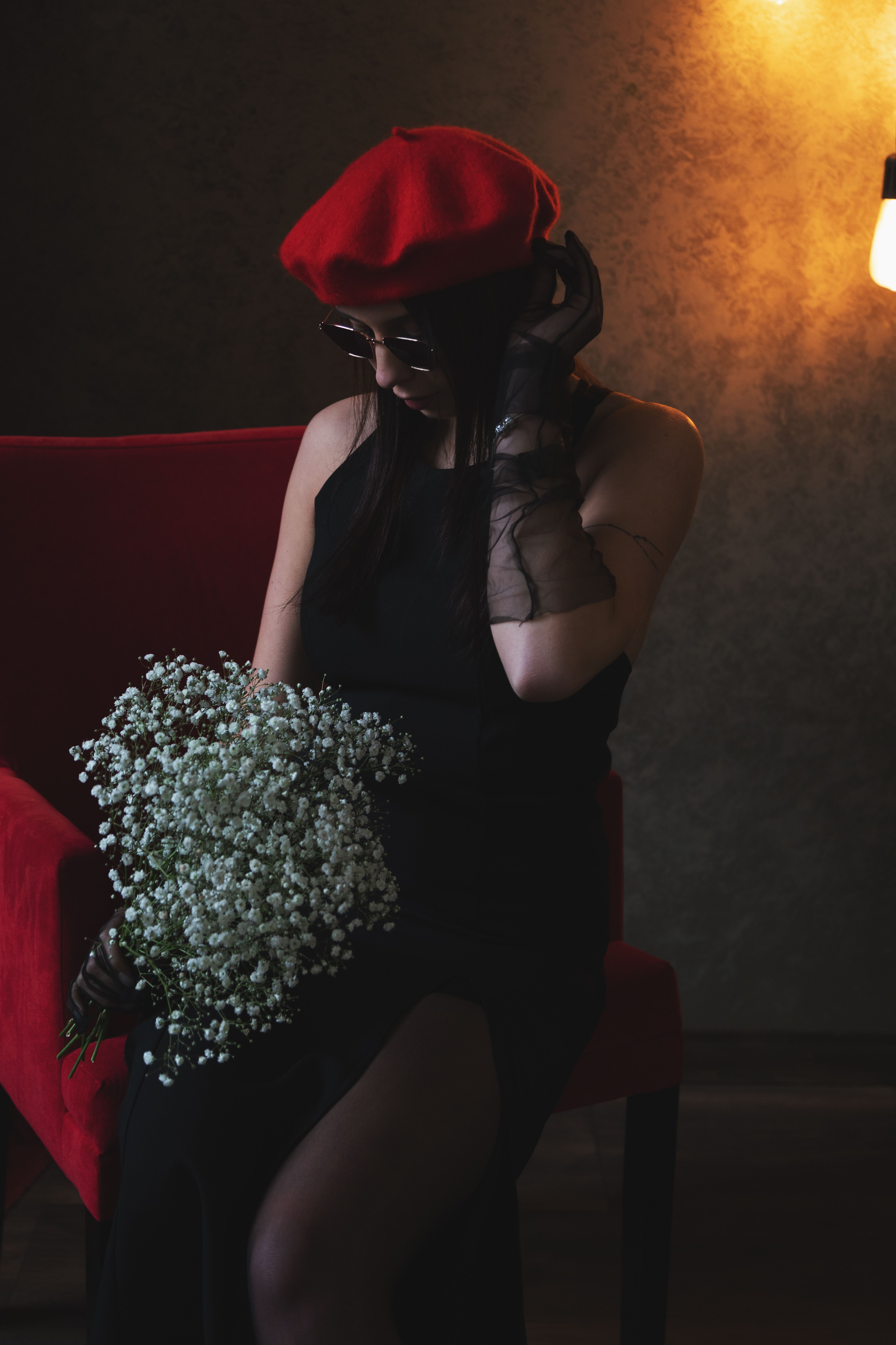 Woman Posing with Flowers on Armchair in Darkness · Free Stock Photo