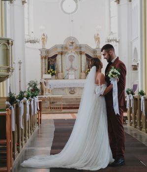 A beautiful wedding ceremony in a grand cathedral with bride and groom embracing. - Fotografer Sidoarjo