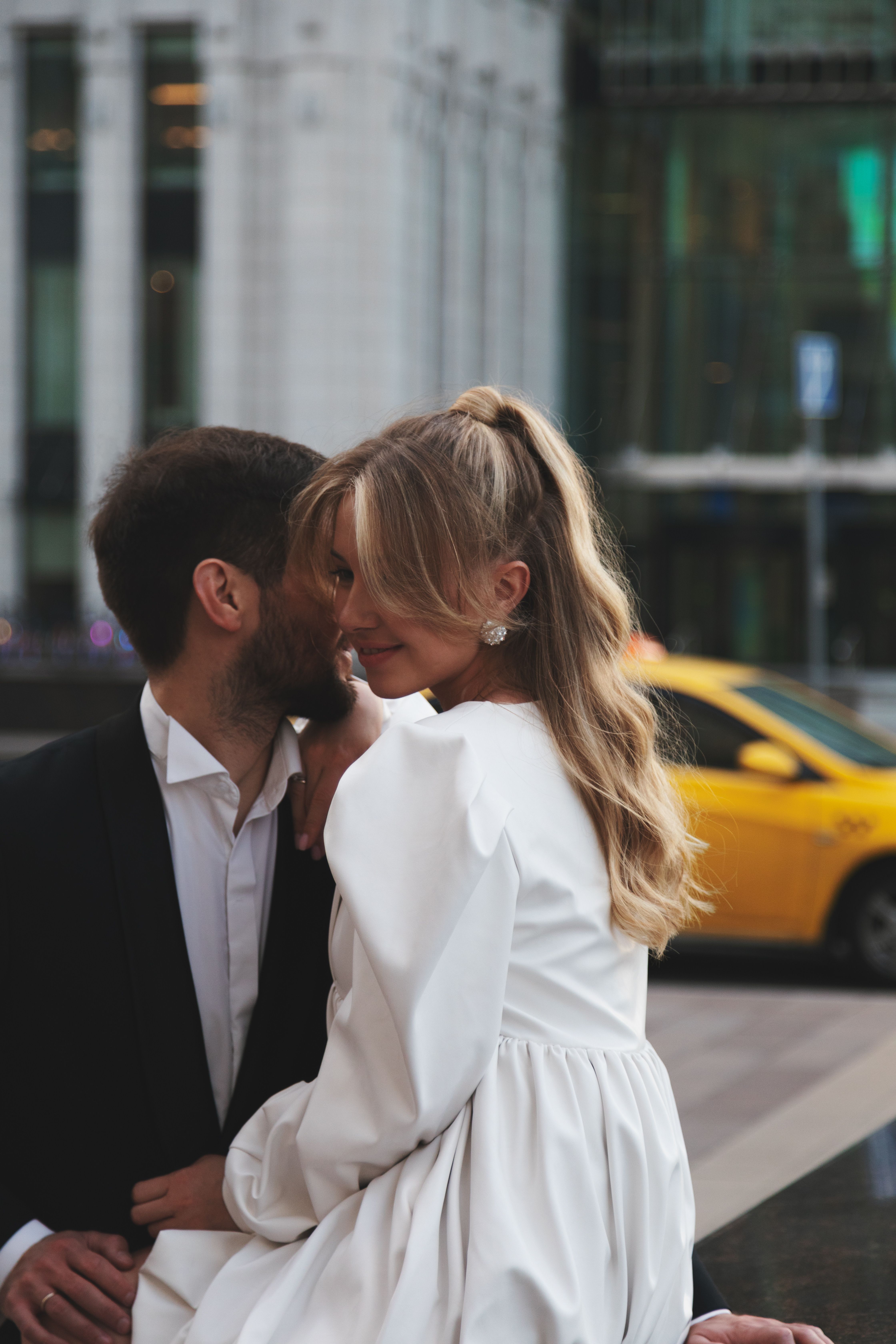 A bride and groom share an intimate moment on a city street, radiating love and happiness.
