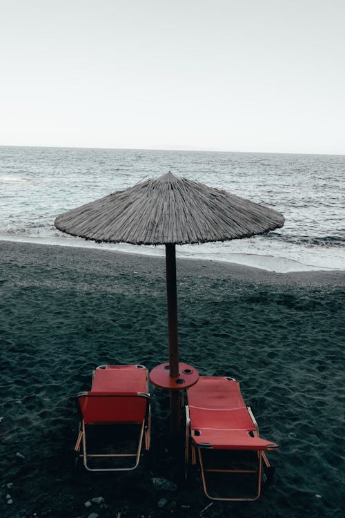 Free Two Red Pool Chairs Under Patio Umbrella Near Shore Stock Photo
