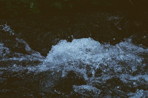 Free Close-up view of water splashing over rocks, capturing movement and texture in a natural stream setting. Stock Photo