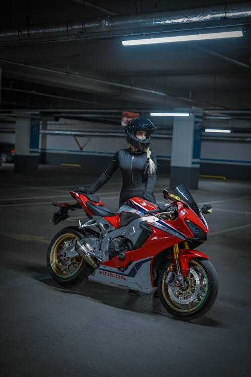 Woman in Helmet Standing near Motorcycle in Underground Parking