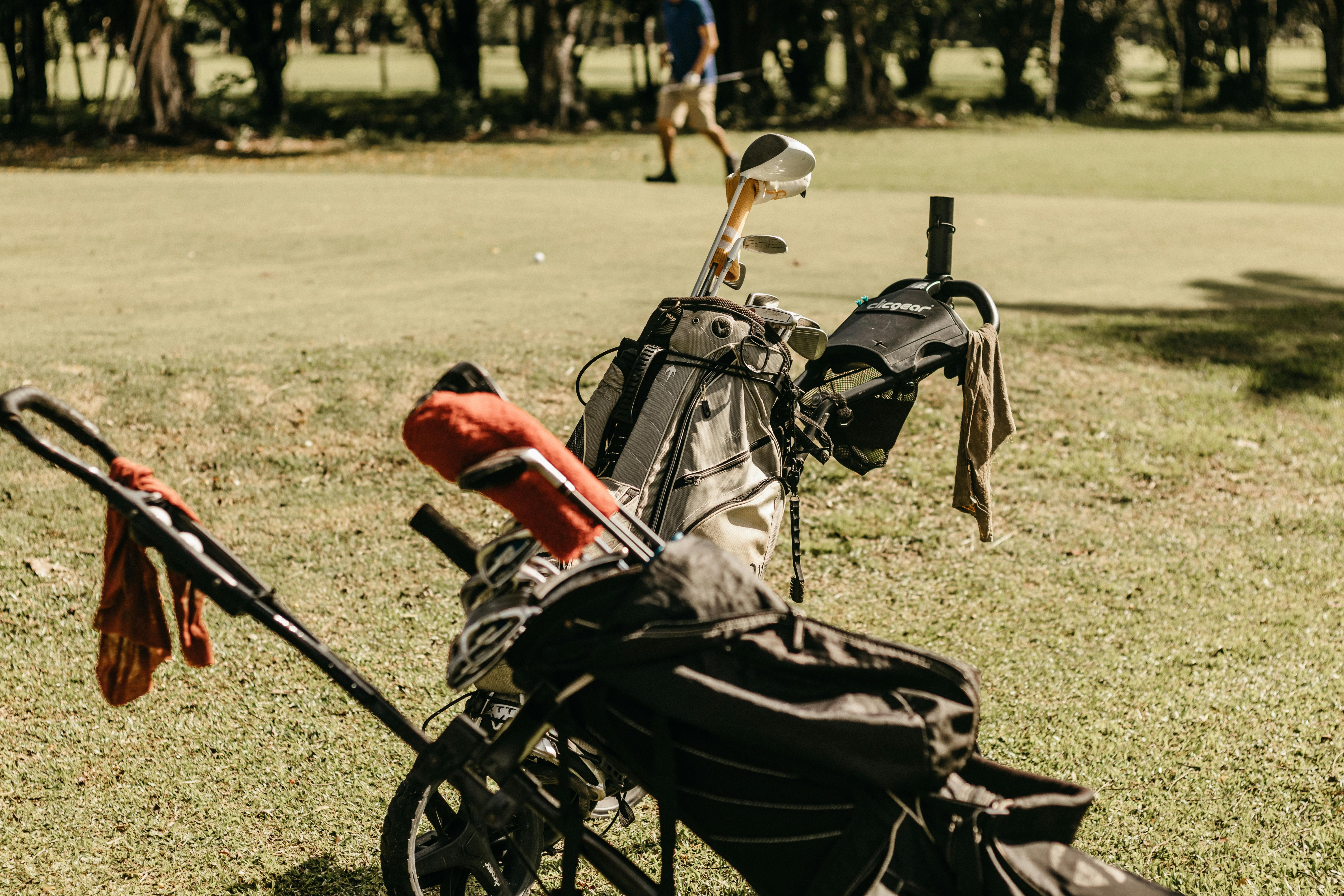 A golf bag and clubs on a sunny golf course, perfect for summer leisure.