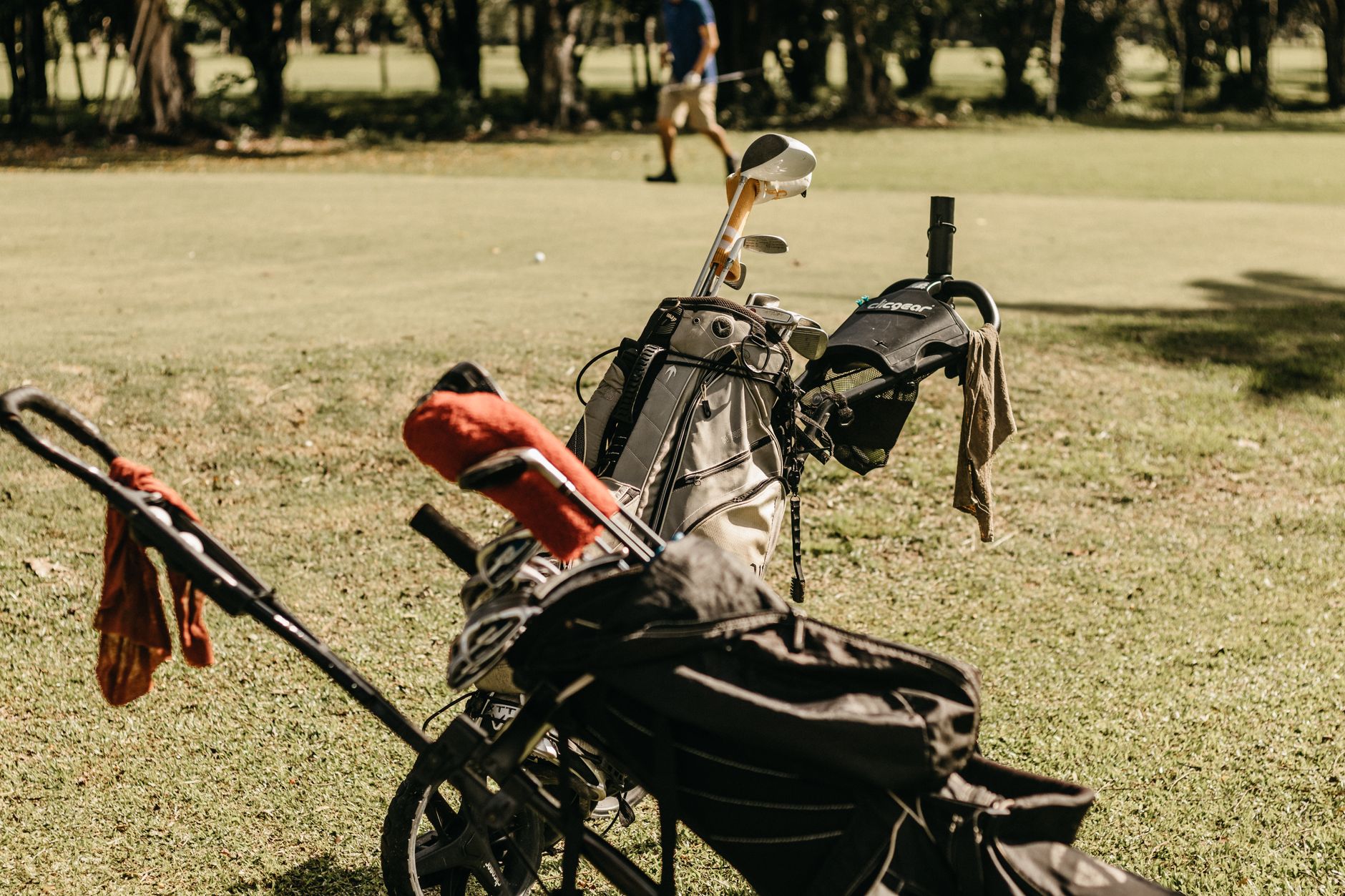 A golf bag and clubs on a sunny golf course, perfect for summer leisure.