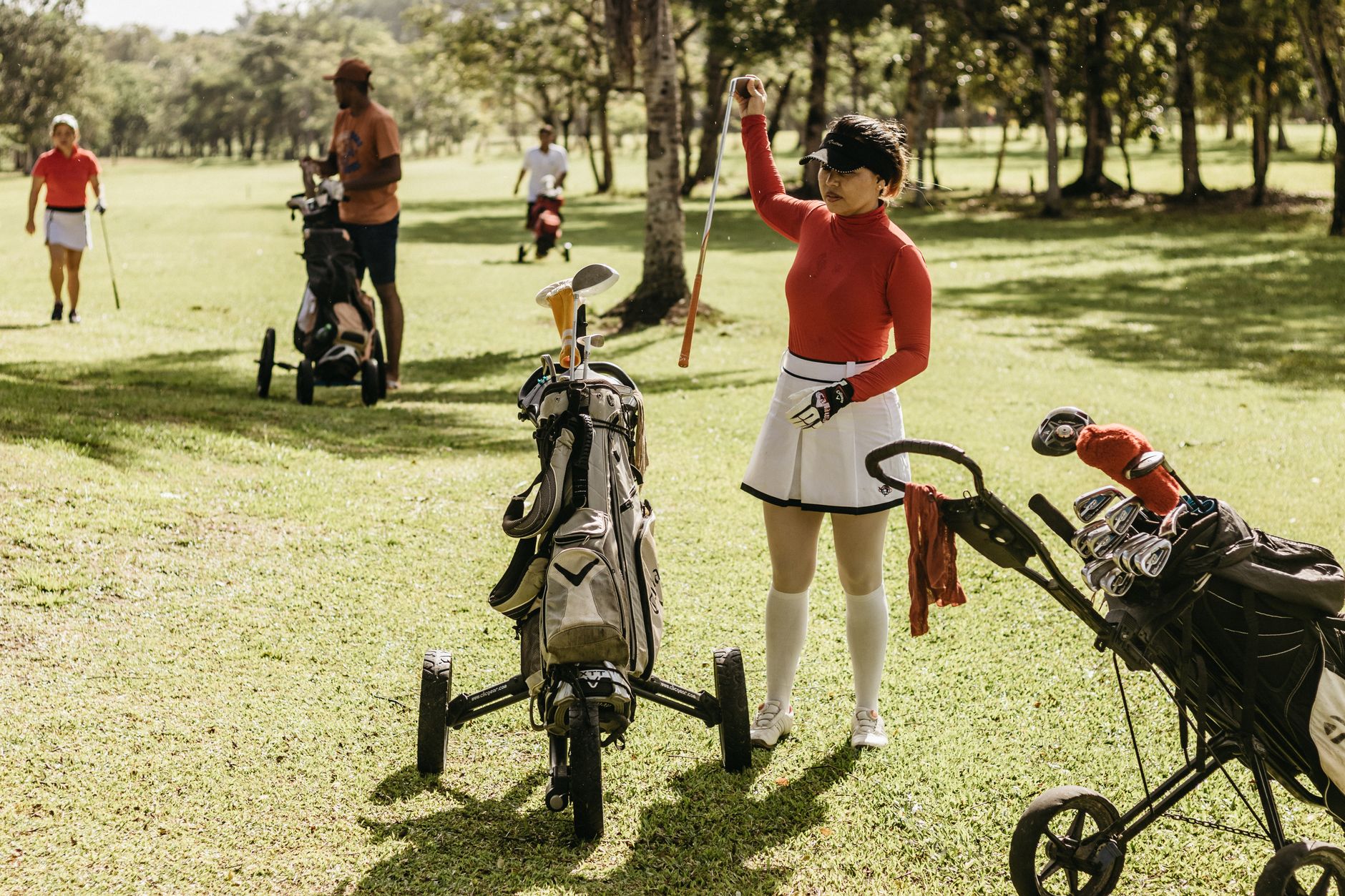 Golfers playing and relaxing on a sunny day at a lush green course.