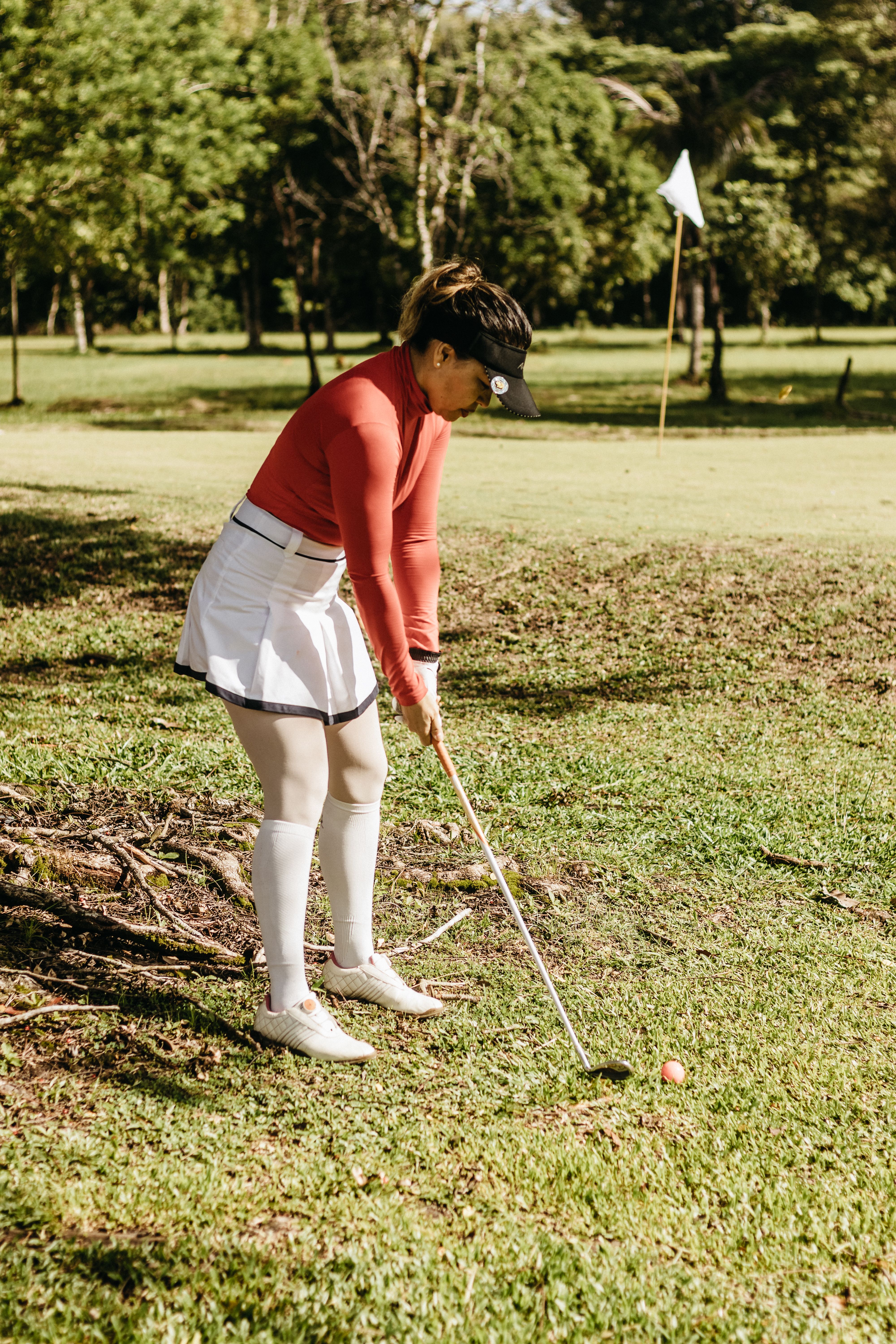 A woman golfer in action on a sunny golf course, showcasing skill and concentration.