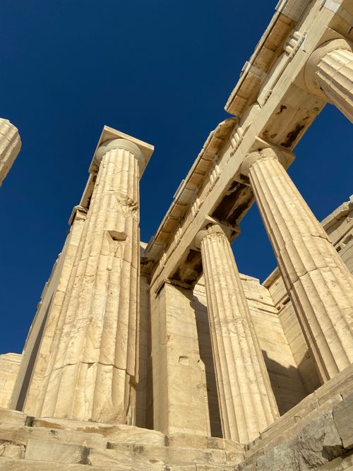 Free Low angle view of sunlit ancient Greek columns under a clear blue sky in Athens, Greece. Stock Photo
