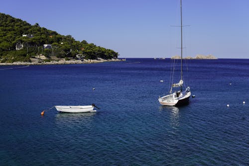 Sailboat and Empty Motorboat on Sea Shore