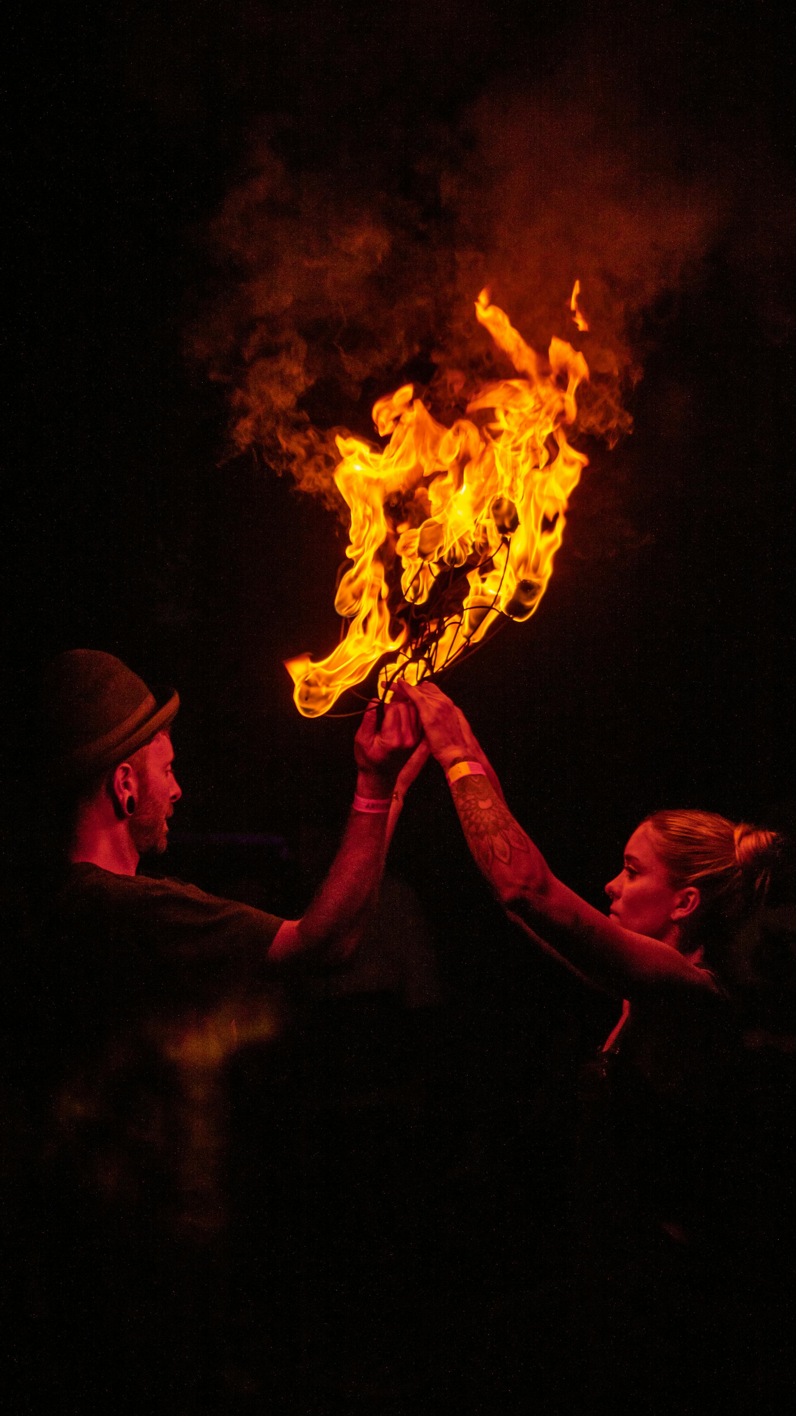 dark photo of a woman and a man holding flaming sticks