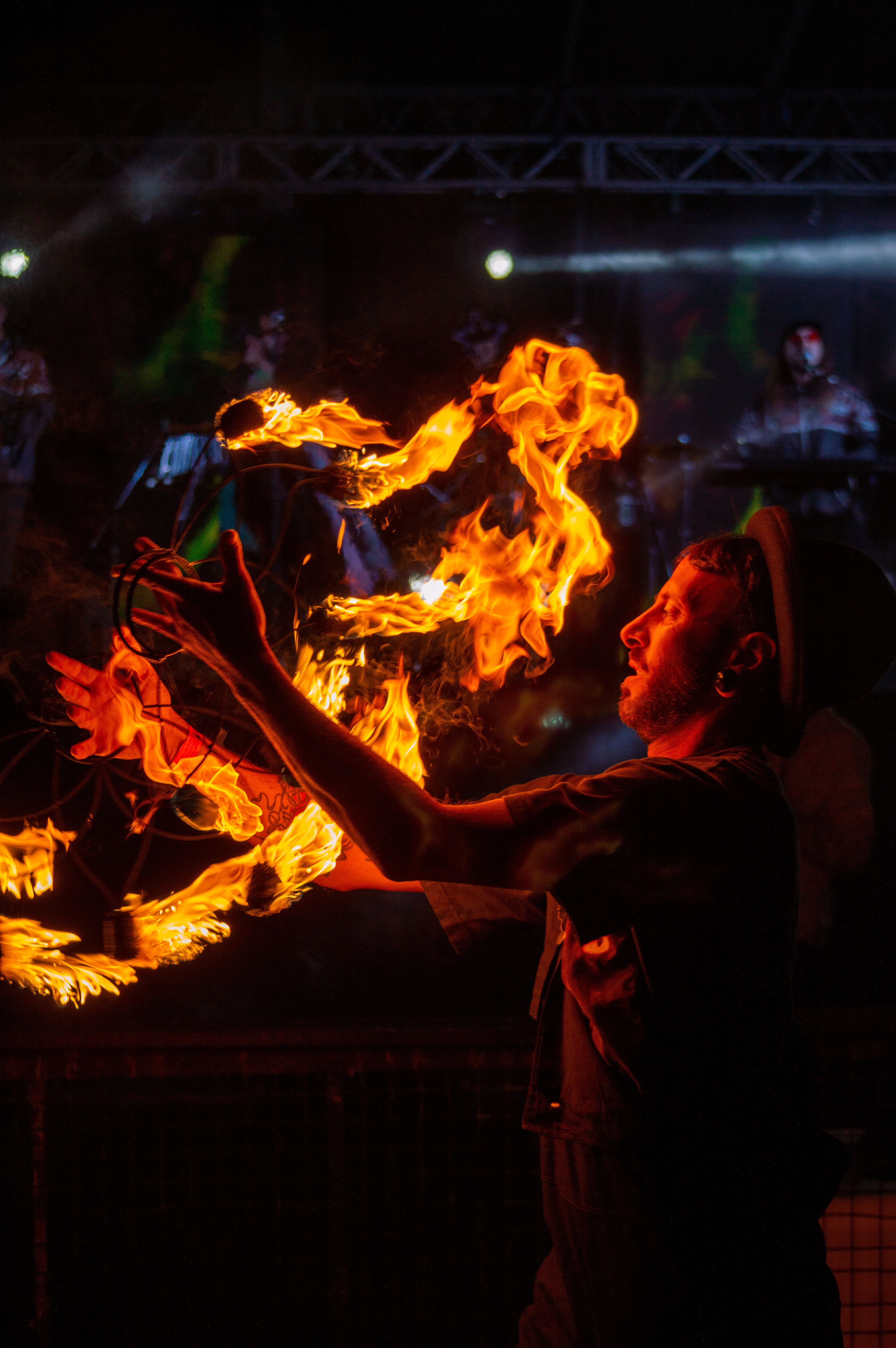 A skilled fire performer juggles flames at a nighttime outdoor event, creating a mesmerizing spectacle.