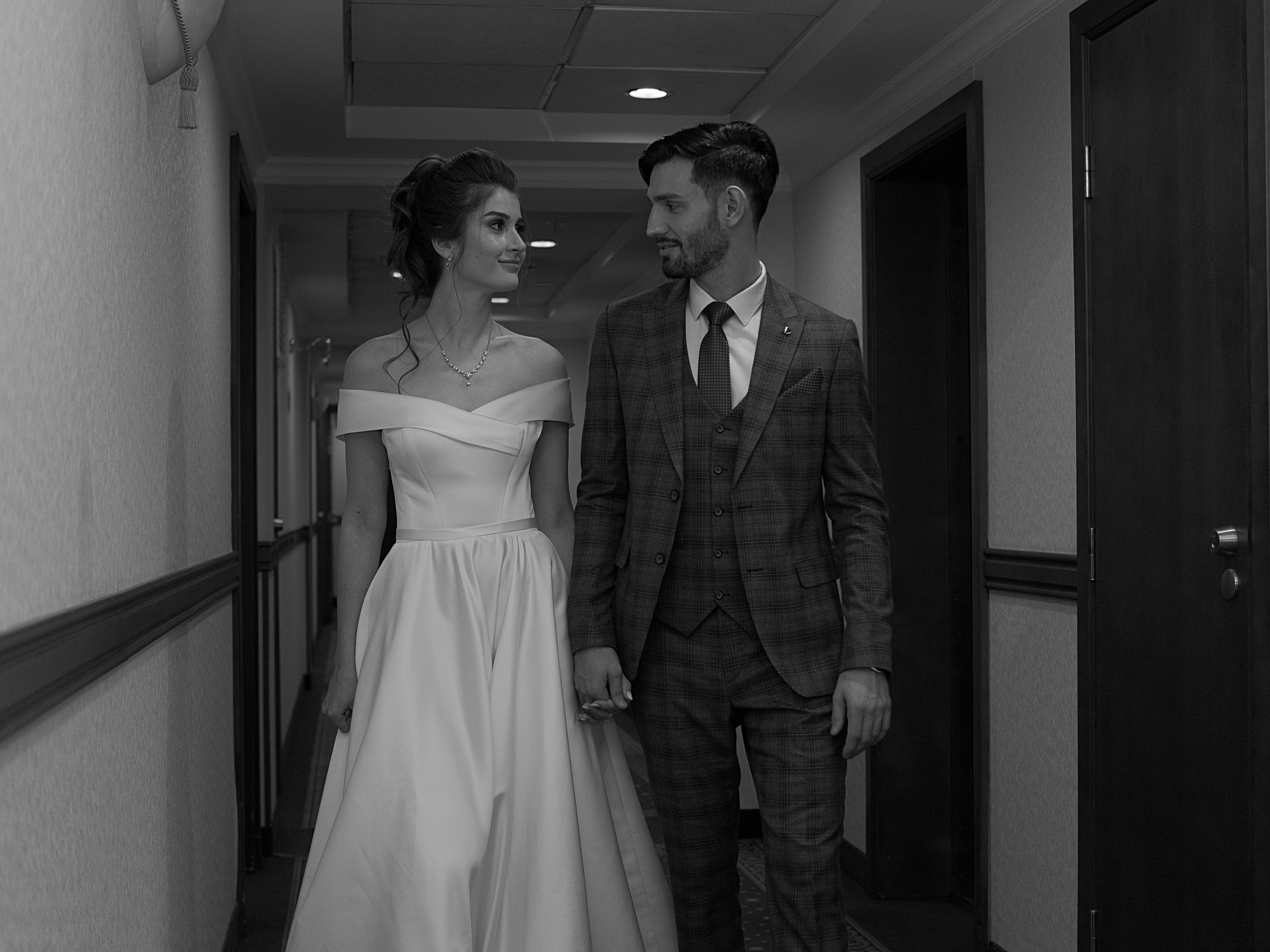 Newlyweds Holding Hands in Corridor in Black and White · Free Stock Photo