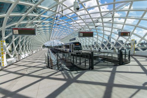 Free Architectural view of a modern railway station with a striking glass ceiling and train platforms. Stock Photo