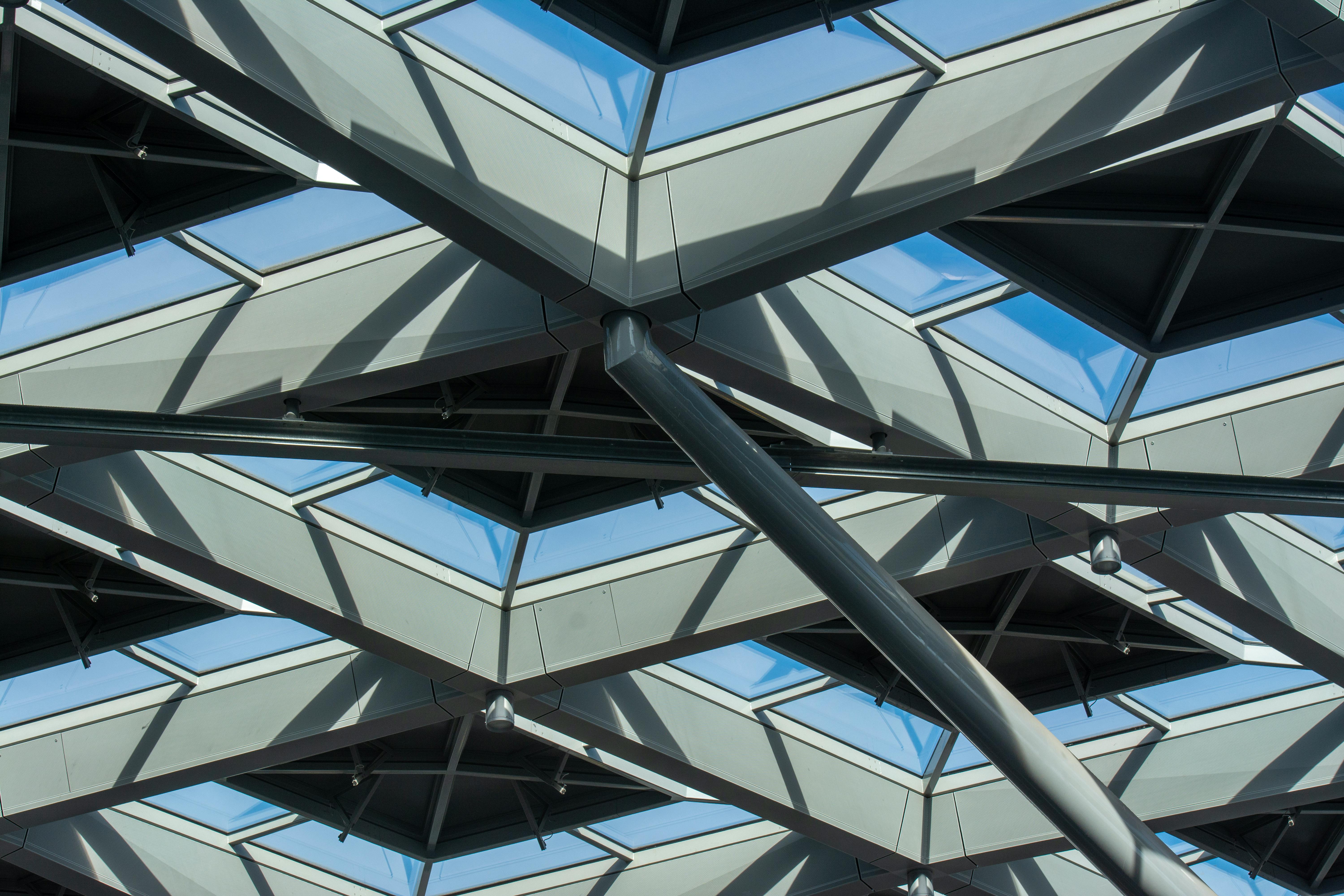 Intricate steel and glass roof design with sunlight and shadows casting patterns.