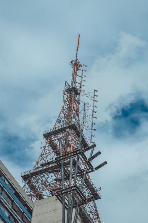 Free A tall metal broadcasting antenna tower reaching toward a clear blue sky Stock Photo