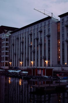 Twilight view of waterfront buildings reflecting on a calm river in an urban setting.