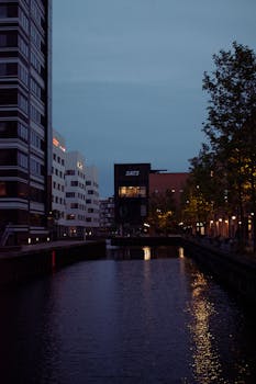 Serene view of an illuminated canal surrounded by modern architecture in Copenhagen at dusk.