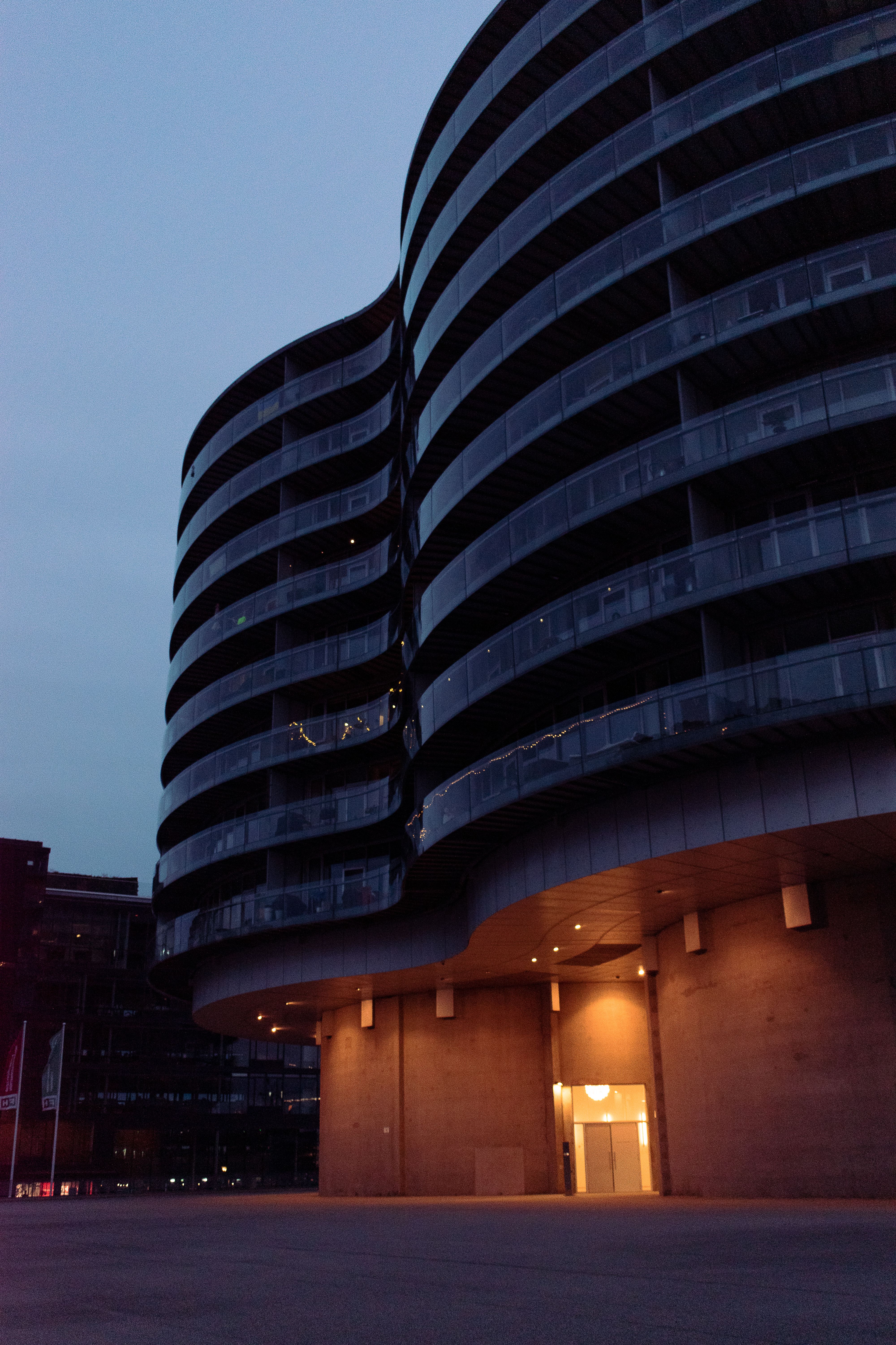 Capture of the Gemini Residence in Copenhagen, with its modern architecture and illuminated façade at dusk.
