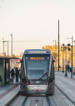 Urban streetcar on tracks in Zaragoza, Spain during sunset, showcasing public transport.