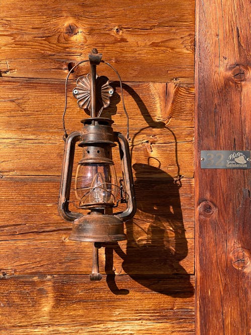 Photo of a Lamp in a Shape of a Vintage Kerosene Lamp on a Wooden Wall