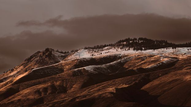 Snow-dusted mountains in Wenatchee, WA under dramatic clouds.