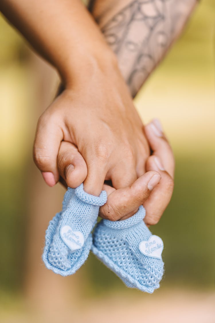 Man And Woman Holding Hands And Baby Shoes