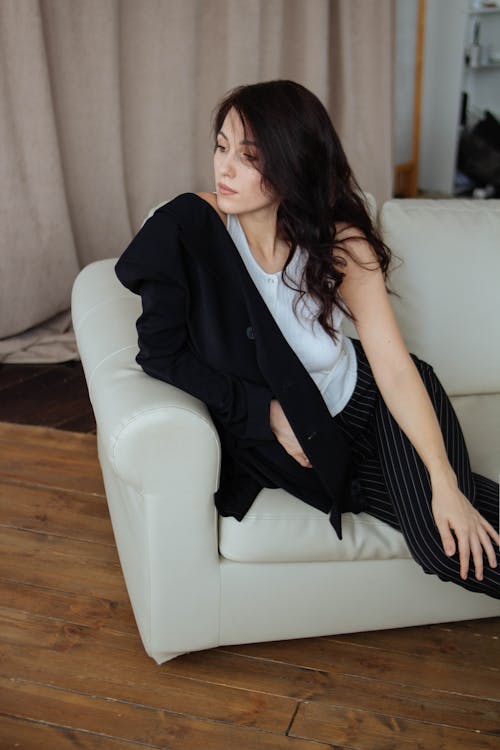 Photo of a Pensive Woman Sitting on a Sofa