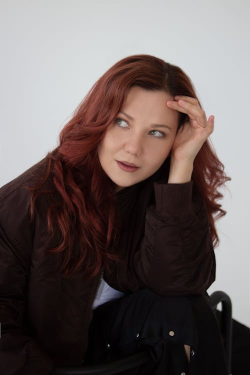 Photo of a Pensive Young Woman Sitting in the Studio