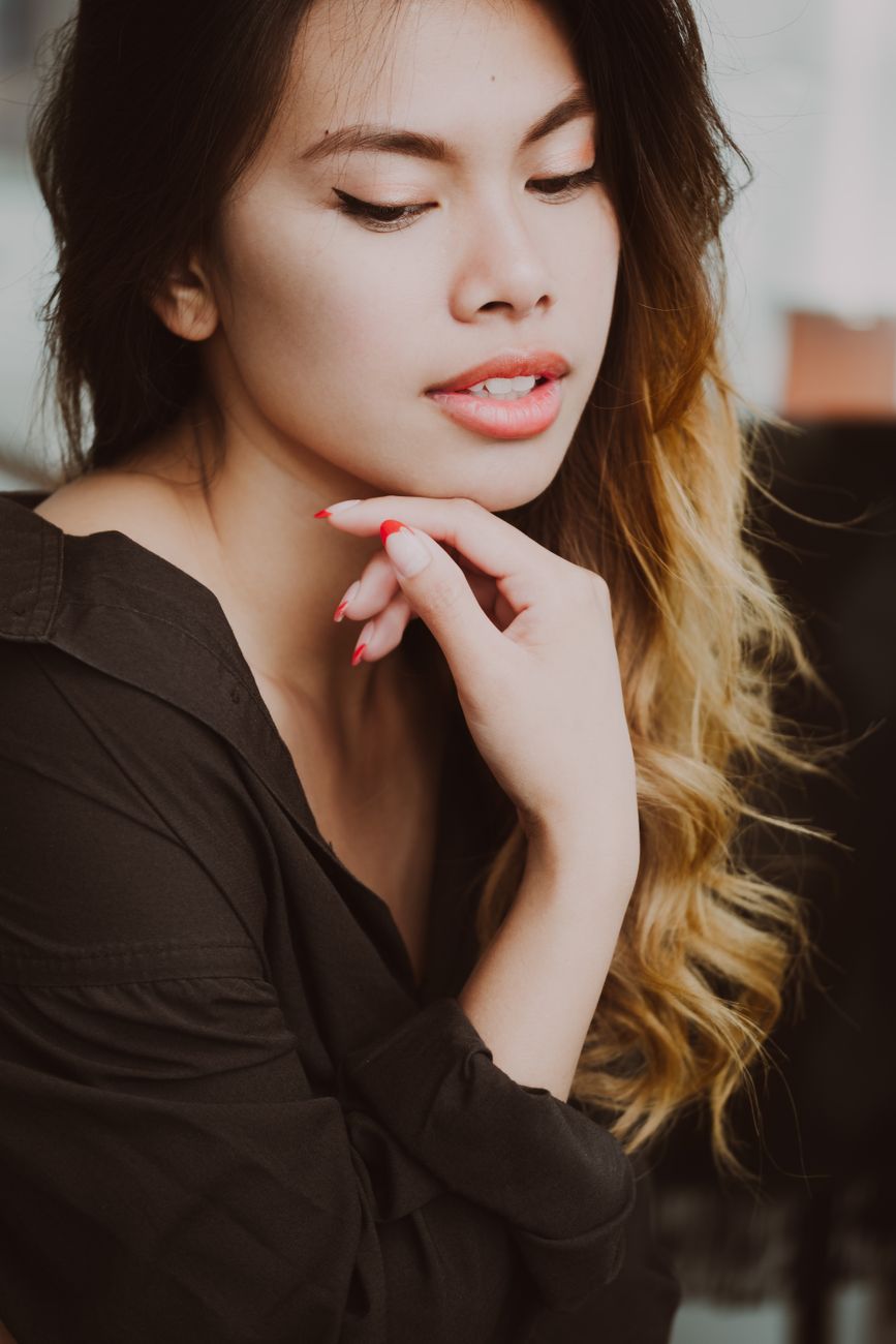 A graceful portrait of a young woman with elegant makeup and relaxed expression in a warm setting.