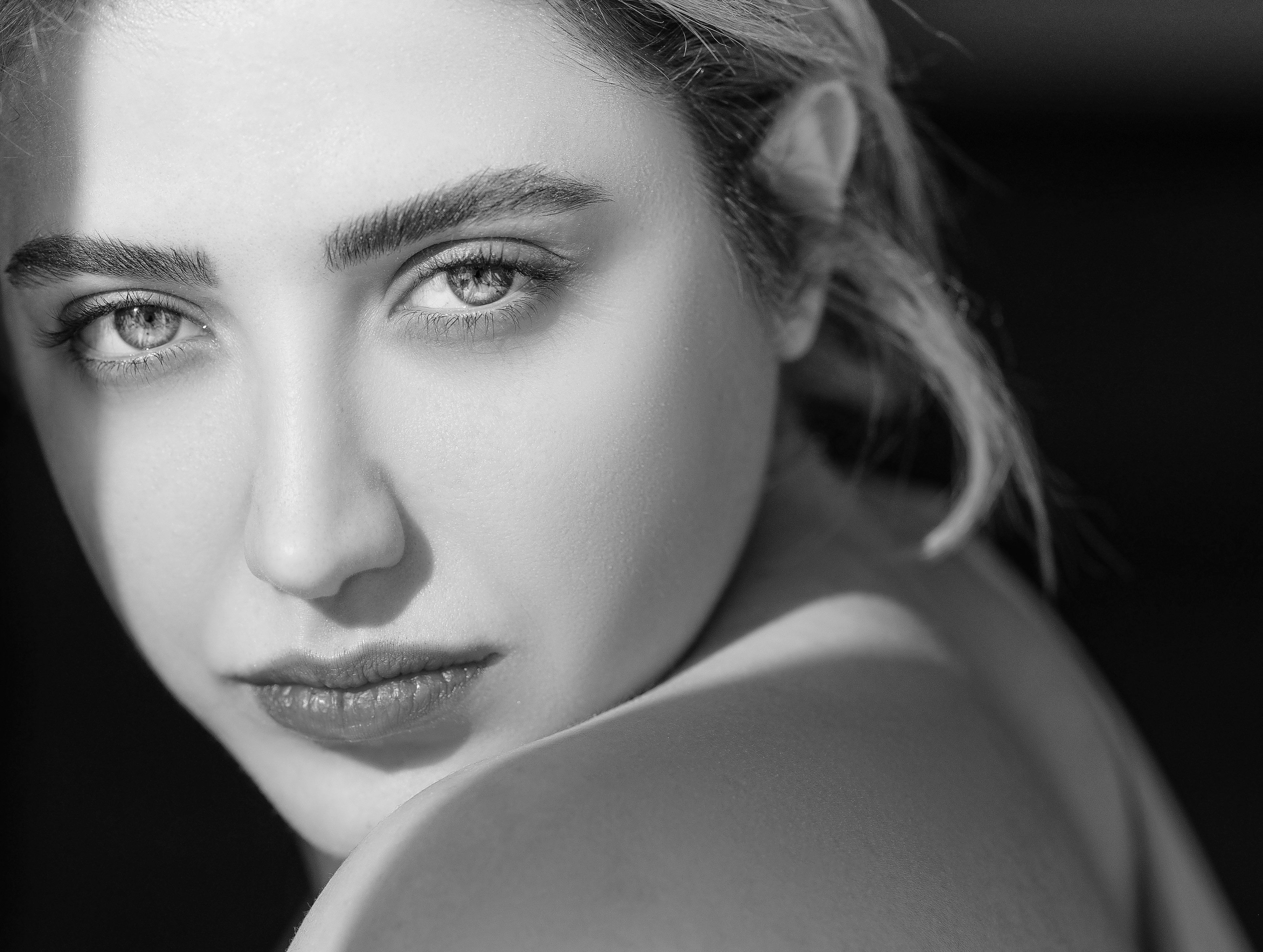 Beautiful black and white close-up portrait of a young woman with a soft gaze.