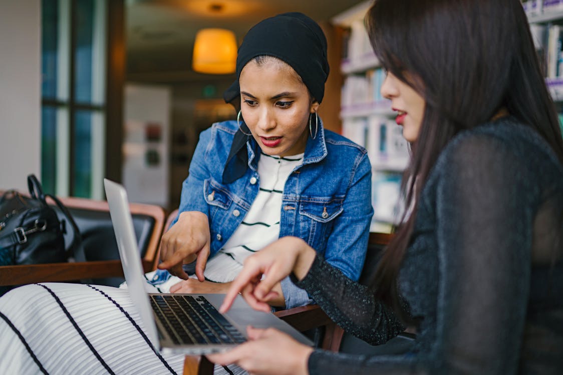 Dua Wanita Melihat Dan Menunjuk Laptop Macbook