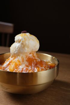Creamy vanilla ice cream drizzled with vibrant orange sauce in an elegant bowl. - Fotografer Sidoarjo