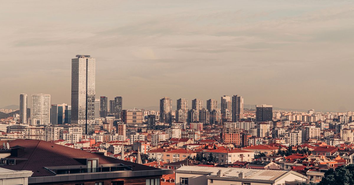 Skyline view of urban cityscape with modern skyscrapers and red brick rooftops under a clear sky.