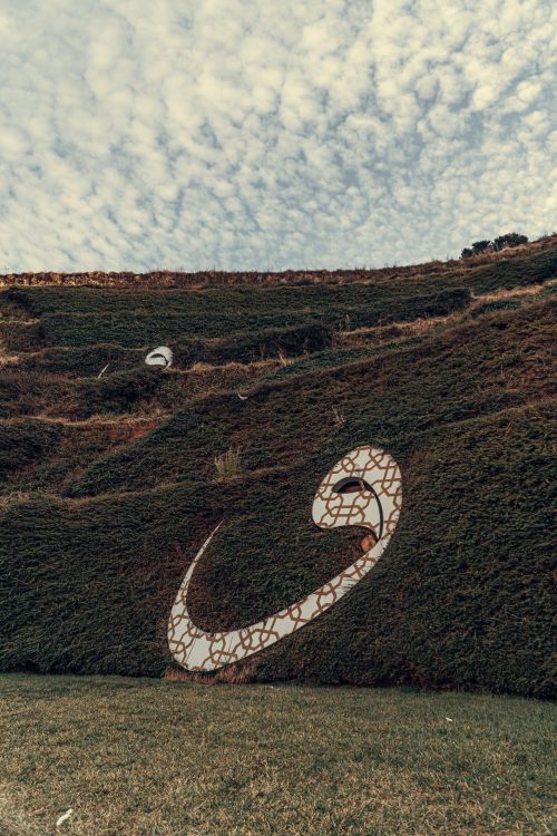 Free A scenic hillside features unique symbolic designs, surrounded by lush greenery under a dramatic cloudy sky. Stock Photo