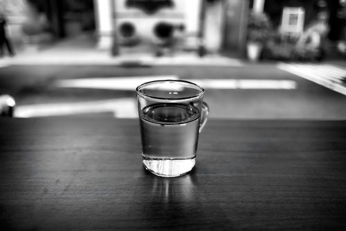 Free Elegant black and white image of a glass of water on a table with blurred background. Stock Photo