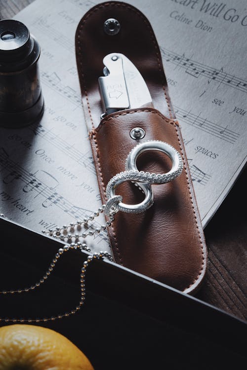 Close-up of a Silver Necklace in a Shape of an Octopus Tentacle Lying on a Multi Tool in a Leather Case