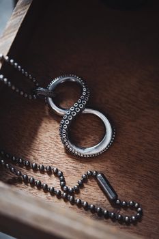 Close-up of a silver octopus tentacle pendant necklace on a wooden background, highlighting intricate details.