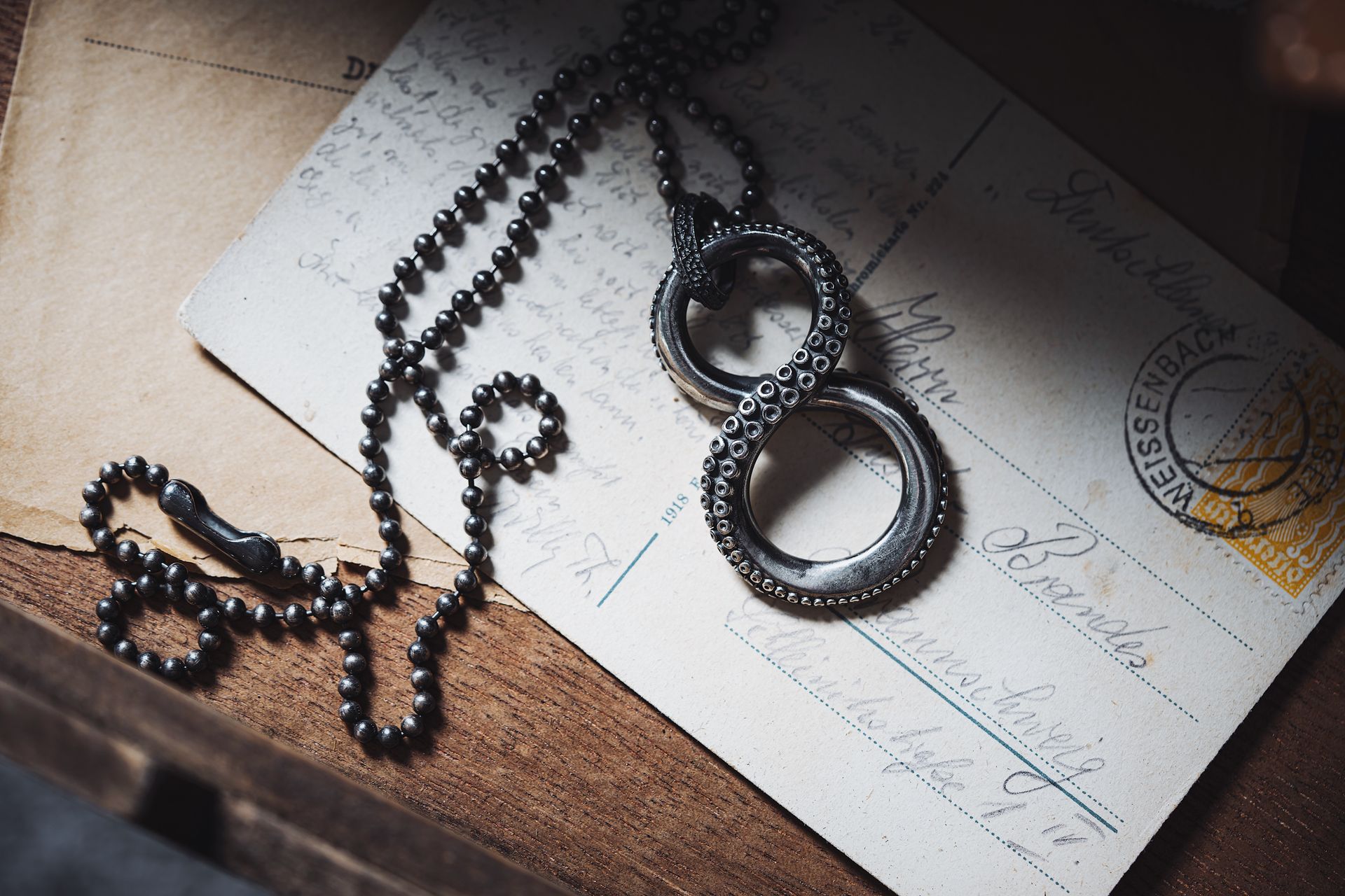 Elegant black necklace with infinity symbol atop vintage postcard.