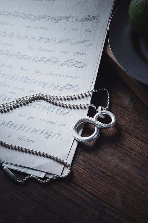 Silver Necklace on Sheet Music on Table