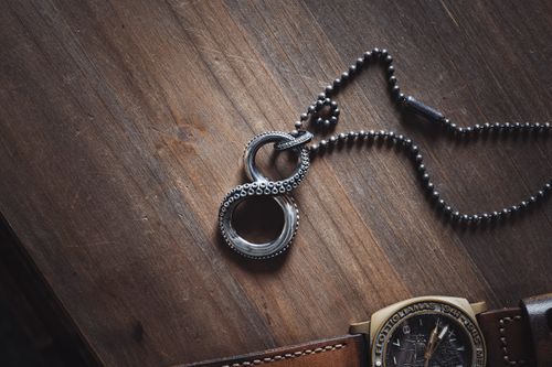 Free Close-up of a metallic infinity necklace on a textured wooden table. Stock Photo