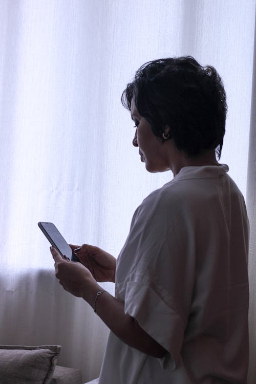 Brunette Woman in White Shirt Holding Phone in Hands