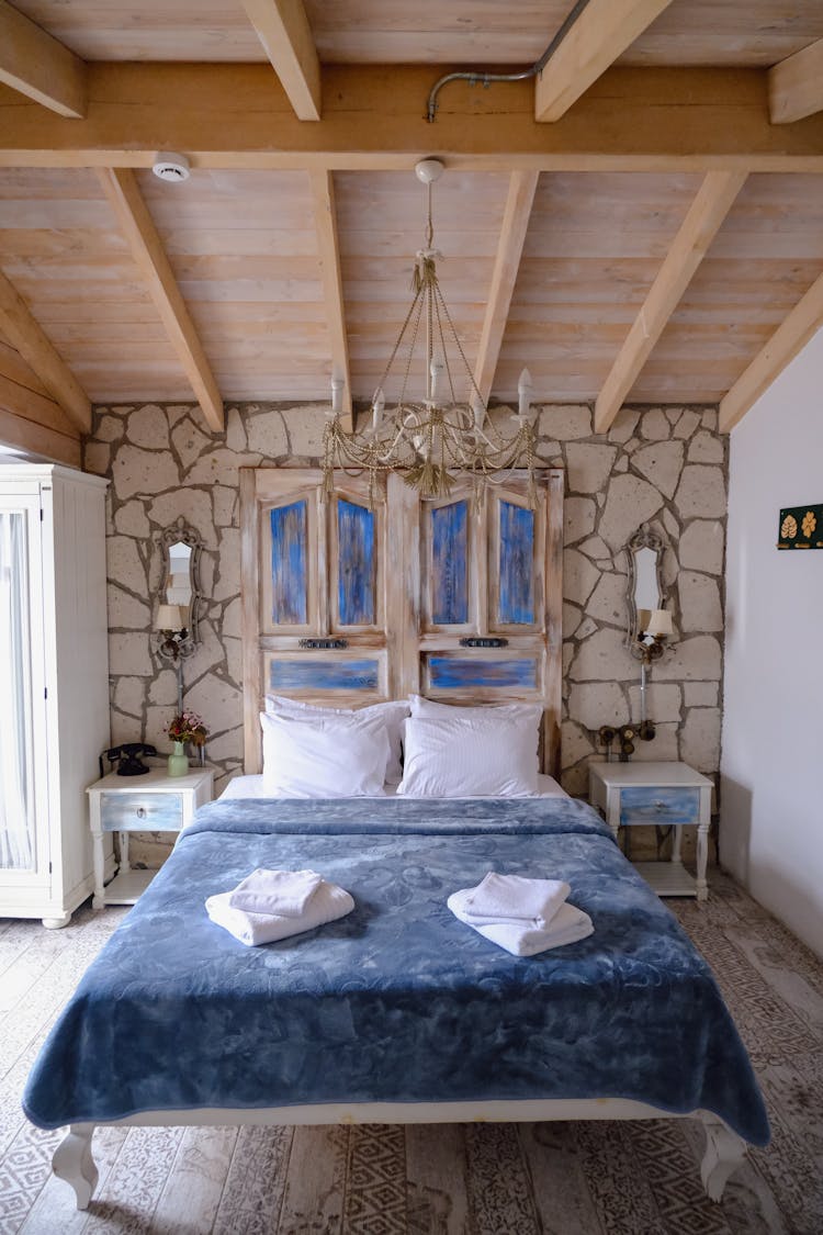 Photo Of A Bedroom With A Wooden Ceiling And A Bed With Blue And White Sheets