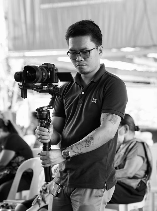 Free Black and white image of a focused videographer holding a professional camera rig at an event. Stock Photo