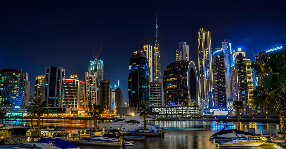 A sleek white private jet sits on a sun-drenched airport tarmac in the UAE under a clear blue desert sky.