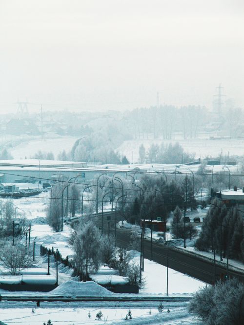 Free A scenic urban view with snowy roads and foggy atmosphere, creating a serene winter landscape. Stock Photo