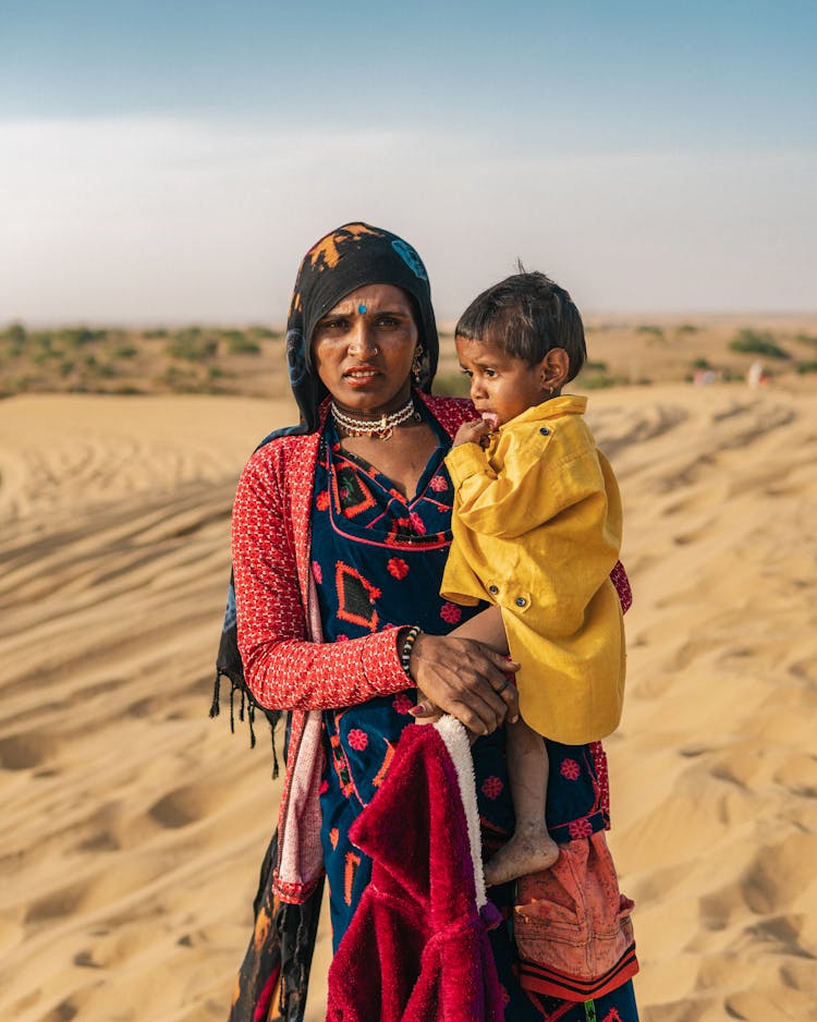 Woman Holding Child On Hands Standing In The Desert