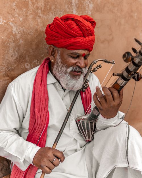 Free A senior Indian man plays the Ravanhatta, wearing traditional clothing and a vibrant turban. Stock Photo
