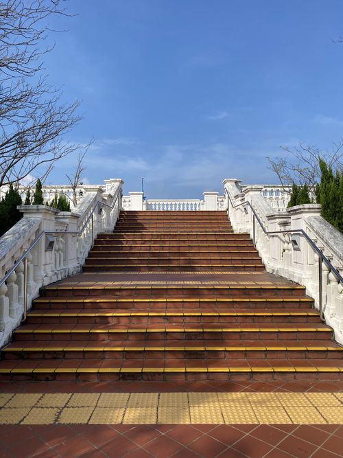 Free A scenic view of a traditional staircase leading to architecture under a bright blue sky. Stock Photo